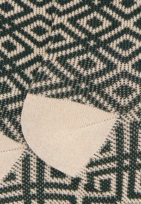 Calze di lana con un motivo geometrico in verde scuro e crema, con tallone e punta rinforzati di colore chiaro.