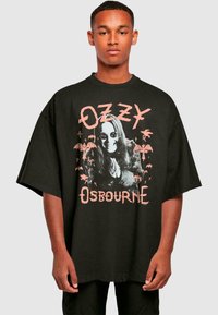 Tricou negru supradimensionat din bumbac, cu un grafic al unei persoane în ochelari de soare, având textul „Ozzy Osbourne” și iluzii cu lilieci.