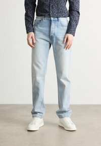 Jeans in denim blu chiaro con taglio dritto, dotati di un classico design a cinque tasche, dettagli cuciti e chiusura con bottone.