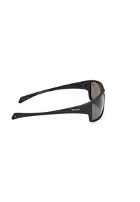 Gafas de sol de plástico negro con lentes ahumados grises, que presentan un diseño aerodinámico y el logo de Timberland en la patilla.