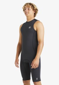 Traje de neopreno negro sin mangas, con un ajuste ceñido, pantalones cortos de longitud hasta la rodilla y un pequeño logo en el pecho. Con costuras planas.