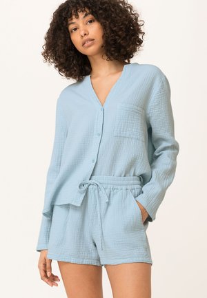 Conjunto de loungewear de algodón texturizado en azul claro que incluye una camisa de botones con un solo bolsillo en el pecho y pantalones cortos con cintura elástica.