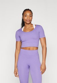 Ljubičasti rebrasti crop top i visokotalasne tajice, sadrži prilagođeni dizajn s kratkim rukavima i okruglim izrezom.