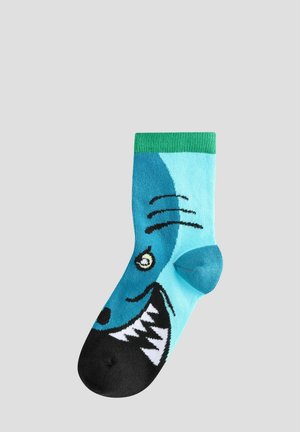 Türkise Socken mit einem Haifischdesign, das schwarze Akzente, einen grünen Saum und ein Muster aus weißen Zähnen aufweist, aus weichem, dehnbaren Material.