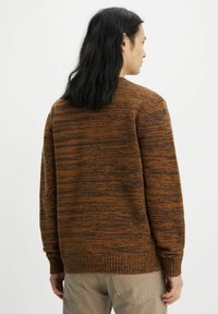 Bruine textuurtrui met een gemêleerd patroon, ribbelmanchetten en onderrand. De achterkant heeft een eenvoudig ronde hals ontwerp.