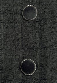 Tissu noir texturé avec deux boutons ronds noirs bordés d'un liseré argenté, disposés verticalement.