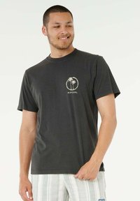 T-shirt in cotone nero con logo frontale di palme e il testo "RIPCURL". Maniche corte e collo a giro.