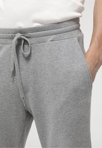 Grå sweatpants i mjukt tyg, med dragsko i midjan, sidofickor och en avslappnad passform. Enkel design utan mönster.