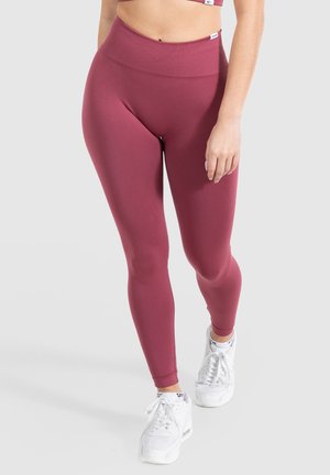 Bordeaux leggings met een hoge tailleband, gemaakt van rekbare stof, strakke pasvorm en gecombineerd met witte sneakers. Soepele textuur, zonder zichtbare patronen.