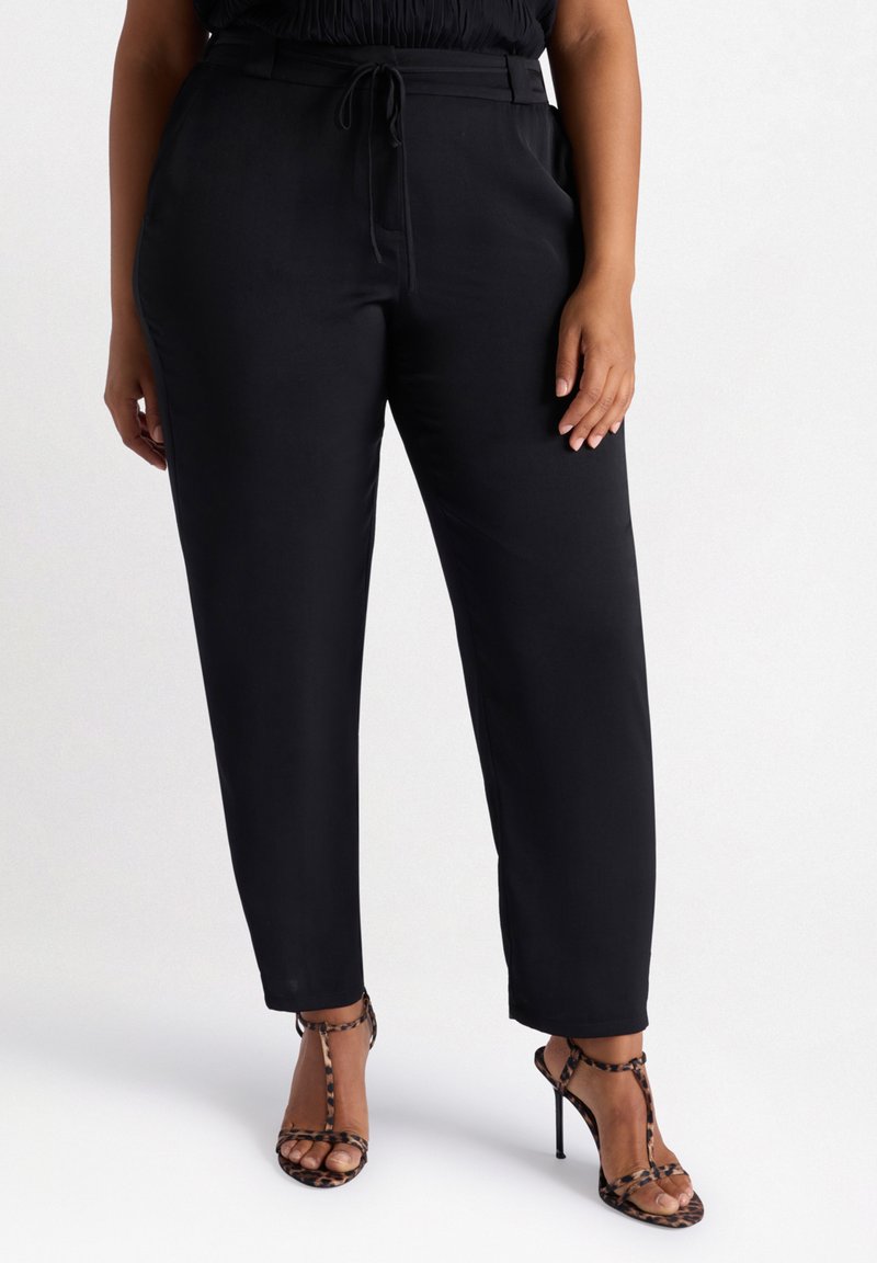 Zwarte, high-waisted broeken met een relaxte pasvorm, een drawstring tailleband en een gladde textuur. Gecombineerd met leopardenprint sleehakken.