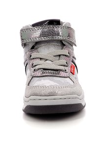 Zapatillas de textil grises con un acabado texturizado, diseño con cordones y una cinta plateada con patrón. Presenta una suela negra contrastante y una marca roja.
