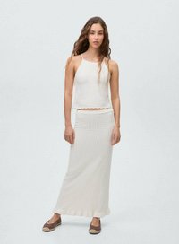 Top court en tricot blanc avec un ourlet festonné, associé à une jupe longue assortie ornée d'un motif texturé et d'un bas à volants.