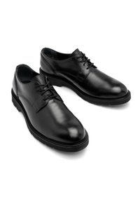 Scarpe da dress in pelle nera con una finitura liscia, punta rotonda e design con lacci. Presentano una suola in gomma robusta e dettagli di cucitura minimalisti.
