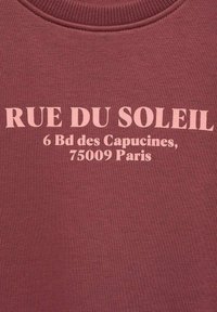 Felpa bordeaux con testo stampato bianco: "RUE DU SOLEIL 6 Bd des Capucines, 75009 Parigi." Tessuto morbido con un design classico a girocollo.