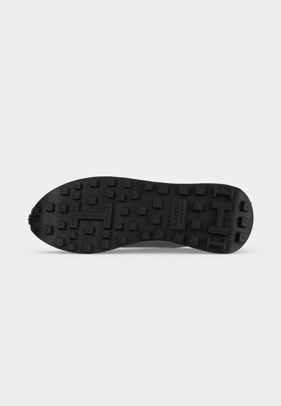 Semelle de chaussure en caoutchouc noir avec des crampons carrés et des formes en relief "H", affichant le nom de la marque Iceberg au centre.
