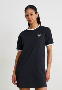 Μαύρο φόρεμα T-shirt με αντίθετο λευκό γιακά και τελειώματα στα μανίκια. Διαθέτει στρογγυλή λαιμόκοψη και λογότυπο στο στήθος. Μαλακό βαμβακερό ύφασμα.