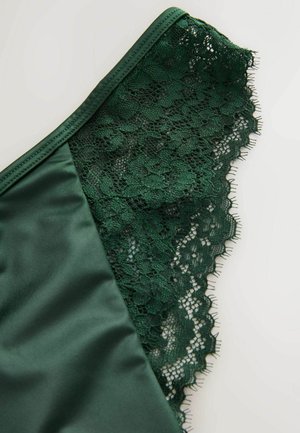 Lingerie verde scuro in morbido satin con delicati bordi in pizzo. Il pizzo presenta motivi floreali e un bordo ondulato.