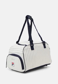 Bolsa de deporte blanca con rayas marinas, material de tela, asas dobles, cierre con cremallera y un pequeño logo en la parte frontal cerca de la base.