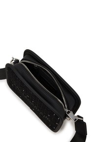 Black crossbody bag featuring a textured woven design, zippered compartments, and silver hardware accents. Soft material, compact shape.