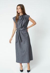 Rochie gri, fără mâneci, cu un guler cowl lejer și un cordon în talie, având modele texturate subtile pe întreaga suprafață și o lungime midi.