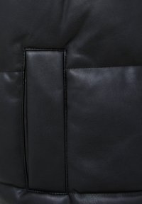 Sac en cuir noir à texture lisse, doté d'un rabat rectangulaire et d'accents cousus pour un détail structurel.