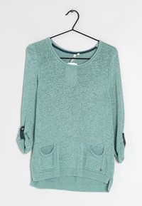 Maglione lavorato a maglia verde chiaro con scollo a barca, maniche a tre quarti, due tasche frontali e dettagli blu scuro vicino ai polsini delle maniche.