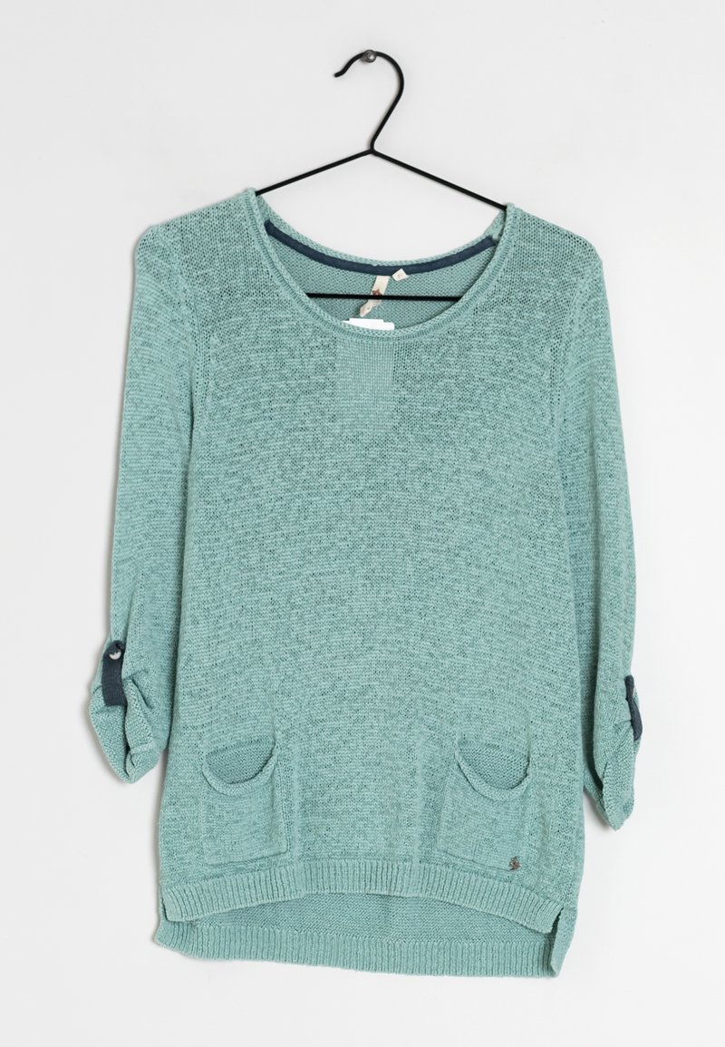 Maglione lavorato a maglia verde chiaro con scollo a barca, maniche a tre quarti, due tasche frontali e dettagli blu scuro vicino ai polsini delle maniche.