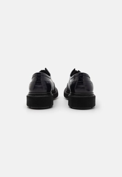 Black patent leather shoes with a rounded toe, textured black rubber sole, and stitching details on the heel and side panels.