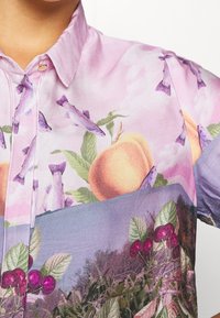 Kurzarmhemd mit einem rosa Hintergrund und einem lebhaften Früchte- und Fischdruck, der Pfirsich- und Kirschmuster mit grünen Blättern zeigt.