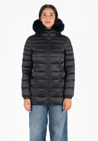 Giubbotto puffo nero con design trapuntato, chiusura con zip e cappuccio foderato in pelliccia. Il giubbotto presenta polsini elastici e una silhouette aderente.