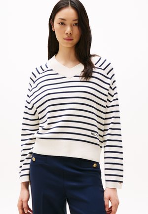 Striped v-neck sweater in cream with navy stripes, knit fabric, ribbed collar and cuffs, light texture, logo detail on lower side.