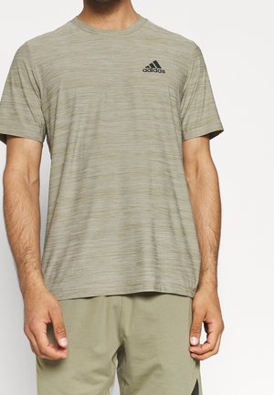 Camiseta deportiva verde oliva hecha de tejido ligero y texturizado. Presenta mangas cortas y un logo negro de Adidas en el pecho.