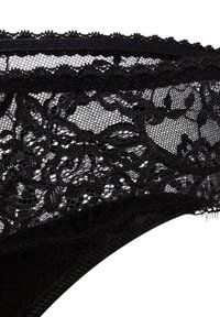 Tanga de encaje negro con intrincados patrones florales, borde escallopado y tejido suave, con textura transparente y cinturilla elástica.