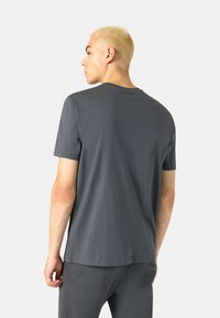 Graues kurzärmeliges T-Shirt aus weichem Stoff mit rundem Halsausschnitt und lässiger Passform, von hinten gegen einen neutralen Hintergrund präsentiert.