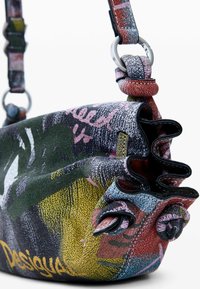 Mehrfarbige Handtasche aus strukturiertem Leder mit abgerundeter Form, detaillierten Verzierungen und einem verstellbaren Riemen mit metallischen Akzenten.