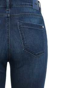 Donkerblauwe spijkerbroek met een aansluitend ontwerp, voorzien van een achterzak en subtiele stikdetails, gemaakt van een zachte, gestructureerde stof.