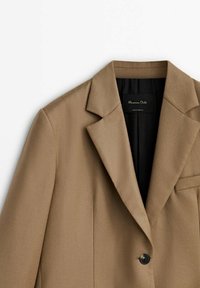 Brun skræddersyet blazer med notch-lapel, enkelt sort knap, brystlomme og sort inderside.