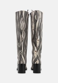 Botas até ao joelho num padrão mármore preto e creme com acabamento brilhante, apresentando um salto quadrado e fecho com zípper nas costas.