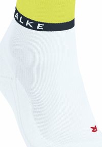 Weißer Sportsocke mit einem gelben Bündchen, versehen mit einem schwarzen Band mit dem Markennamen und einem kleinen roten Logo an der Seite.