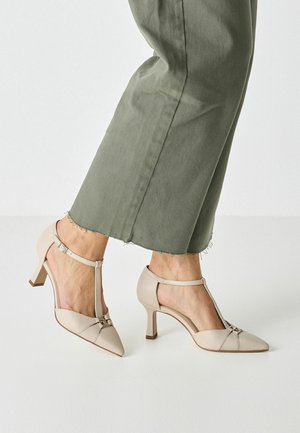 Beige high-heeled shoes with pointed toes and ankle straps. Made of smooth leather, featuring a small buckle detail and a sturdy heel.