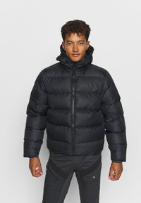 Giacca a vento nera con colletto alto, chiusura con zip e design trapuntato. Realizzata in materiale liscio e isolante per garantire calore.