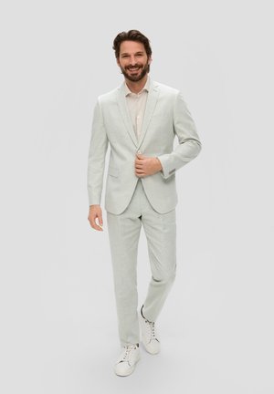 Helles graues, strukturiertes Anzug, kombiniert mit einem hellen Hemd und weißen Sneakers; umfasst ein tailliertes Blazer und gerade geschnittene Hosen.