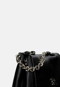 Borsa a tracolla in pelle nera con finitura testurizzata, dotata di manico in catena argentata e chiusura con zip. Marchio ben visibile sul lato.