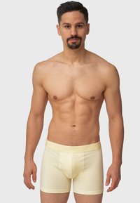 Gule bomull boksershorts med myk tekstur; elastisk belte med "INDICODE" preget. Klassisk passform med beskjeden dekning.