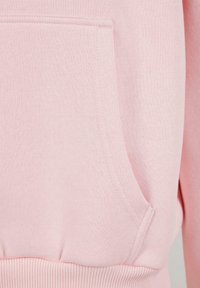 Ljusrosa hoodie-tyg som visar en framficka, ribbad fåll och en slät textur med subtila sömnadsdetaljer.