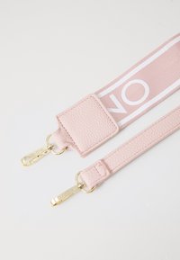 Rozā ādas siksna ar zelta detaļām un baltu logo rakstu. Iespējotas teksturētas virsmas un divi klipi piestiprināšanai. Izturīgs un stilīgs dizains.