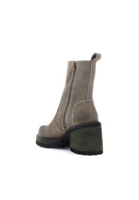 Botines de ante gris con cremallera lateral, tacón texturizado verde, puntera redondeada y costuras blancas en contraste.