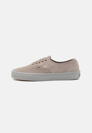 Beige suède sneakers met een laag ontwerp, een grijze rubberen zool, zes veterogen en een Vans-logo label aan de zijkant. Glad textuurafwerking.
