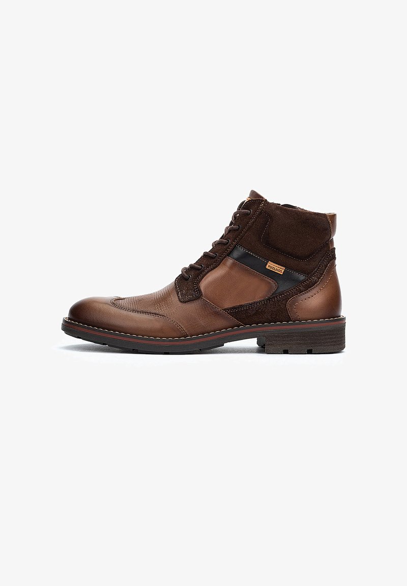 Bruna läderankelboots med mockadetaljer, snörningsdesign, en kontrastpanel och texturerad yta; gummisula med sömnadsdetalj.