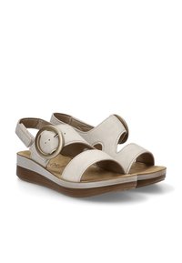 Sandalias de cuero beige con puntera redondeada, laterales abiertos, correa de tobillo y hebilla circular, que cuentan con una plantilla acolchada y un tacón bajo.